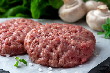 Raw burger patties on white paper, raw minced pork.