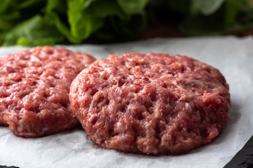 Raw burger patties on white paper, raw minced pork.