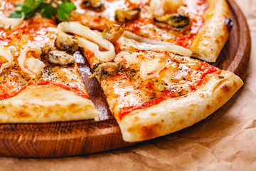 Italian Pizza with seafood and mozzarella cheese on wooden cutting board. Close up