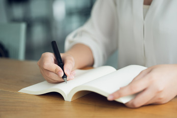 Business woman, traveler, article writer Hold the pen to write the text in the empty book. Record, memorize, memorize or record important items.
