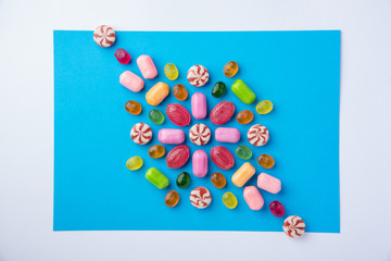 Many multicolored delicious candies on a blue background