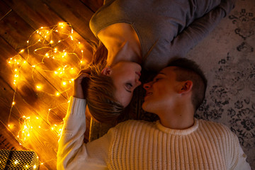 Happy couple at home lying on the floor. Top view. Magic lights