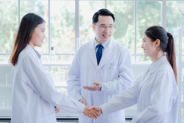 The asian scientists shake hands coworker. Professor doctor introduce new colleague researcher in biotechnology and pharmacy in hospital lab. Hospitality Science, chemist, biology education concept.