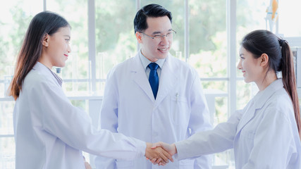 The asian scientists shake hands coworker. Professor doctor introduce new colleague researcher in biotechnology and pharmacy in hospital lab. Hospitality Science, chemist, biology education concept.