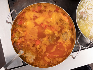 Kharcho soup in a large pan on the stove, next to other soup, top view