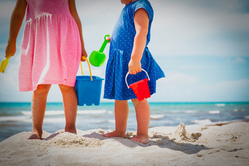 girls dig play with sand on beach