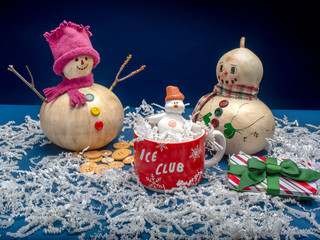   Winter scene, snowman family with child in a mug of ice.
