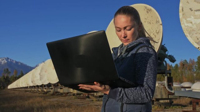 Woman student operator of institute of Solar Terrestrial Physics monitors communication equipment in notebook. Unique array solar radio telescope. Sun Solar Radio Telescope. The 'Quasar' observatory