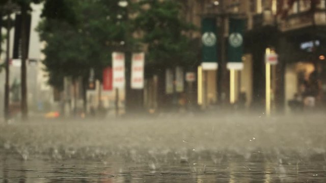 Background of heavy rain day on city street. Real time. Woman on a bicycle is passing by. Blurred bokeh. Naturale backdrop