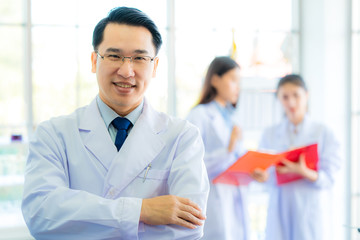  A middle aged man scientist smiling happily with his arms crossed posing at her laboratory colleagues. A confident professor CEO standing preparing equipment for teaching collage student. Copy space.