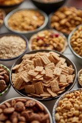 Close up and selective focus. Composition of different kinds cereals placed in ceramic bowls with cornflakes, granola, cereals and oatmeal. Flat lay, top view on white wooden table.