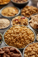 Close up and selective focus. Composition of different kinds cereals placed in ceramic bowls with cornflakes, granola, cereals and oatmeal. Flat lay, top view on white wooden table.