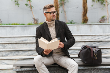 Handsome man wearing jacket reading a book