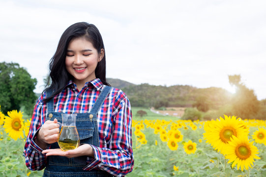 Young women bottle of oil against sunflowers - Image