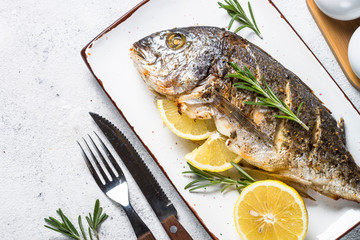 Baked dorado fish with lemon and rosemary top view.