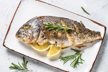 Baked dorado fish with lemon and rosemary top view.