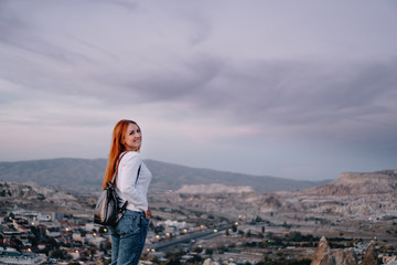 young woman tourist stands against mountain landscape