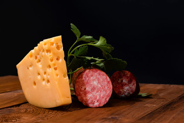 a large slice of delicious cheese with sliced salami sausage on the table