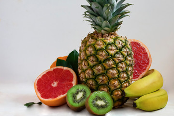 big ripe pineapple with sliced tropical fruits on the table