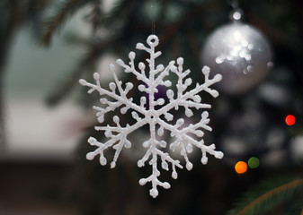 New Year's decorative snowflake hanging on a fir-tree branch