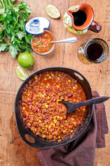 Traditional slow cooked Mexican chili con cane with mincemeat, beans and corn as top view in a modern design cast-iron roasting dish