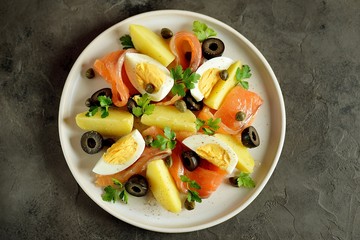 Salad of salted salmon, boiled potatoes, chicken eggs with olives, capers, parsley and olive oil.