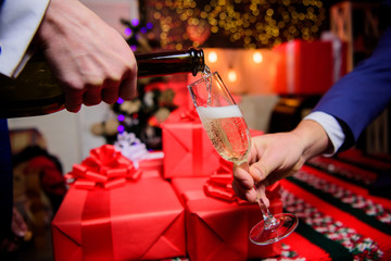 Drink champagne or sparkling wine. Celebrate new year with champagne. Cheers concept. Hands pouring champagne into elegant glass christmas decorations background. Last minute before new year