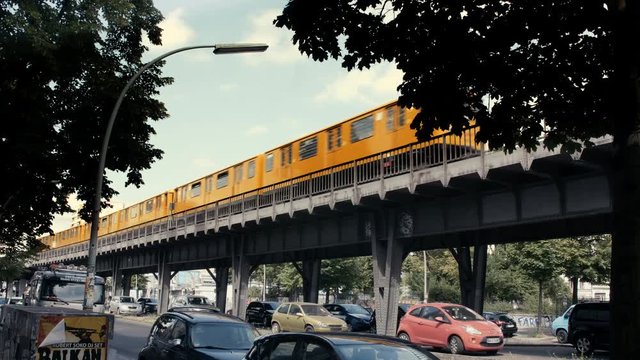 Berlin Metro Train (U-Bahn) passing by in sunny weather, Cars parked below