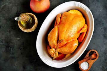 Whole raw chicken marinated in olive oil, soy sauce, white wine vinegar with turmeric, thyme and apple slices. Top view. Copy space. 