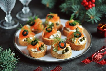Canapes with cream cheese, salted salmon, capers, olives and dill.