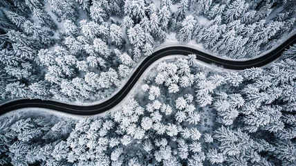 Foto op Canvas Curvy windy road in snow covered forest, top down aerial view © marcin jucha