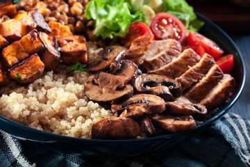 Vegetable buddha bowl lunch with chicken and quinoa, chickpea, mushrooms, lettuce and tomatoes