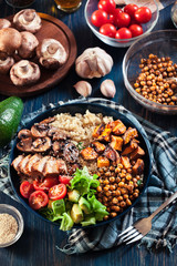 Vegetable buddha bowl lunch with chicken and quinoa, chickpea, mushrooms, lettuce and tomatoes