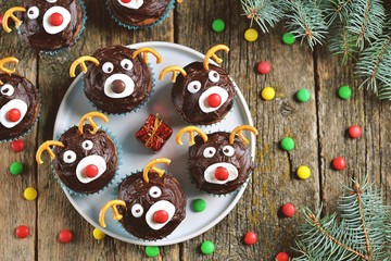 Homemade funny cupcakes Santa's reindeers on a wooden background. Christmas idea for kids.