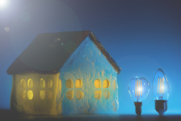 Led lamps stands near the house layout on a blue background.