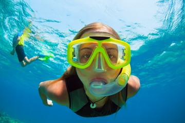 Happy girl in snorkeling mask dive underwater with tropical fishes in coral reef sea pool. Travel lifestyle, water sports, outdoor adventure, swimming lessons on family summer beach holiday with kids