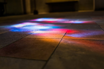 Colorful reflections of stained glass murals on stone ground low angle closeup