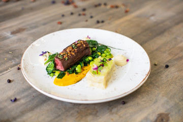 Beef meat with green peas, sweet potato mousse, roasted spinach and zucchini gratin
