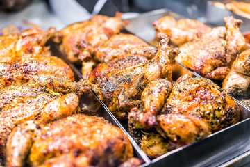 Many whole chicken roasted closeup on tray in deli display store shop grocery brown with herbs, golden skin spicy, crispy