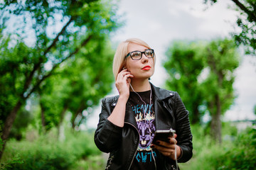 girl in glasses listening to music on headphones in nature