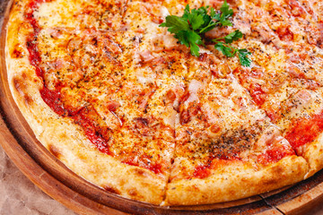 Italian Pizza with bacon, tomatoes and mozzarella cheese on wooden cutting board. Close up