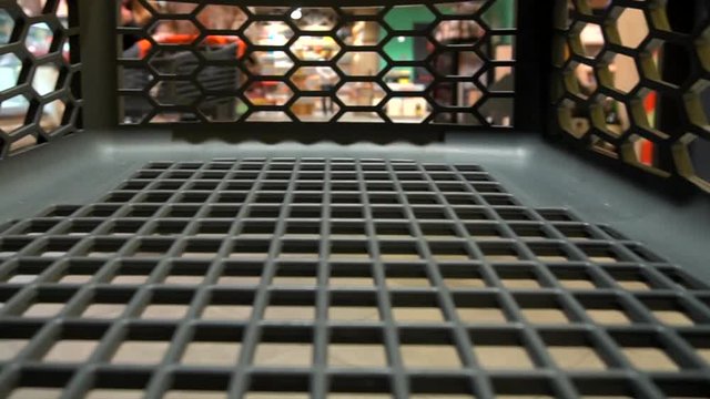 Empty shopping cart quickly rides in a grocery store. View from a shopping cart trolley into supermarket, close-up. Shopping tour in a grocery shop with winter holidays decoration.