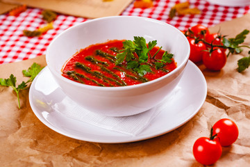 Tomato cold gazpacho soup with pesto sauce in white bowl. Close up