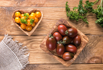 Dark red and yellow tomatoes in wooden bowls
