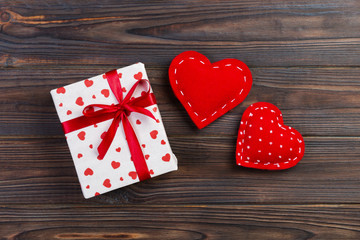 Valentine or other holiday handmade present in paper with red hearts and gifts box in holiday wrapper. Present box of gift on Dark wooden table top view with copy space, empty space for design
