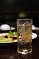Cold Beer in glass and ice and food on table, Beer is Beverage Alcohol in foods shop night time (selective focus)