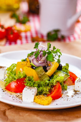 Greek salad with vegetables and feta cheese on white plate. Close up
