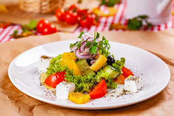 Greek salad with vegetables and feta cheese on white plate. Close up