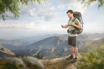 Wanderer vor weitem Bergpanorama schaut aufs Smartphone