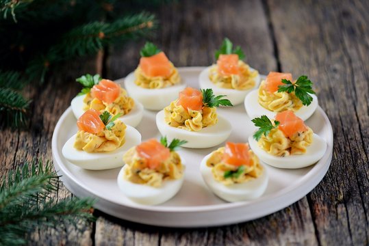 Stuffed chicken eggs with soft cheese, capers and salted salmon. Christmas background.